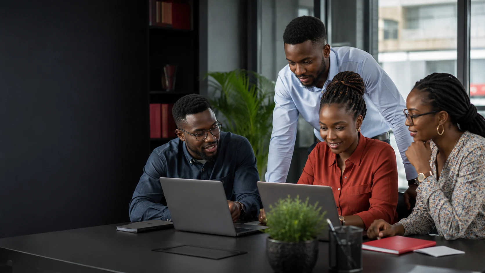 Illustrative African technology team collaborating on laptops in a modern office